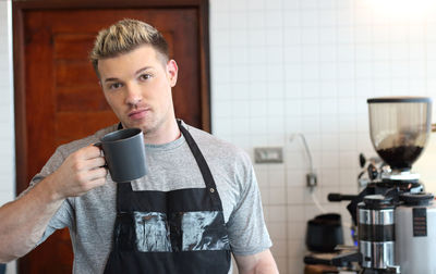 Portrait of young man drinking coffee at home