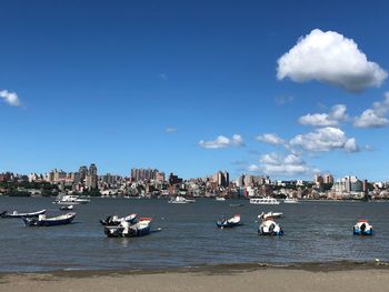 Boats moored on sea by buildings against sky