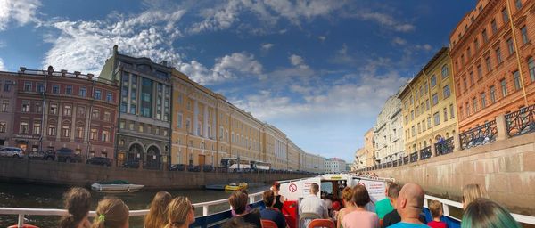 People on street amidst buildings in city against sky