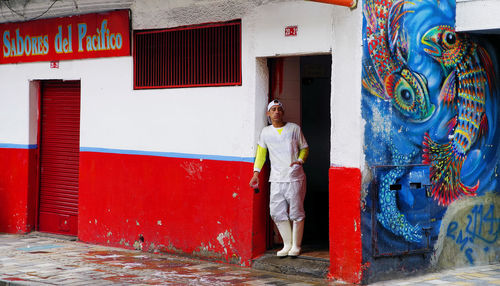 Full length of man standing against graffiti wall