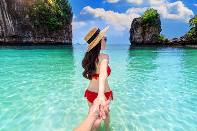 Woman with arms raised in sea against sky