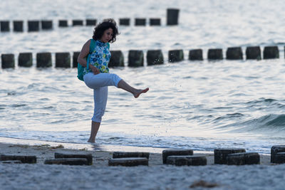 Full length of woman splashing on beach