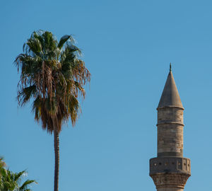 Low angle view of tree by building against clear blue sky