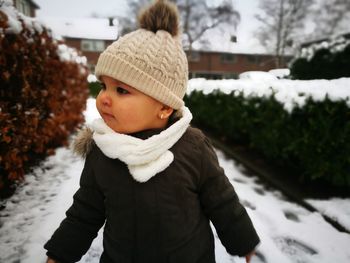 Cute baby girl wearing warm clothing while standing on snow