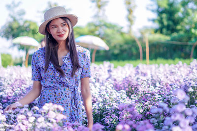 Young woman wearing hat standing against plants