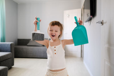 Cute european child with blue scoop for garbage and brush for sweeping floor 