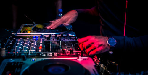 Midsection of dj playing music at nightclub