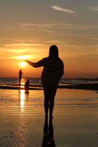 Silhouette woman standing on beach during sunset