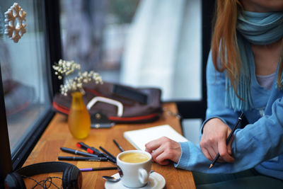 Midsection of woman working with coffee on table