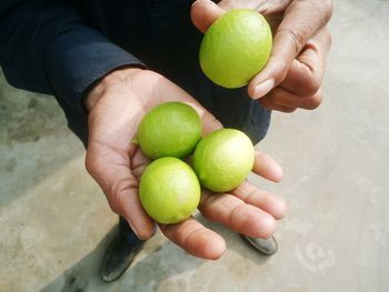 Low section of man holding lemons on footpath