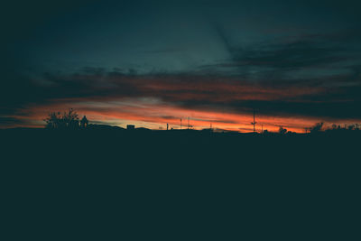 Silhouette landscape against dramatic sky during sunset