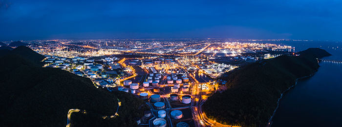 High angle view of illuminated city by sea against sky