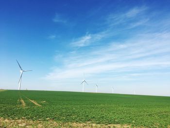 Wind turbines on field against sky