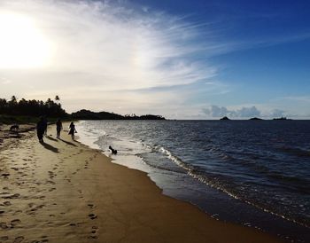 People walking on beach against sky