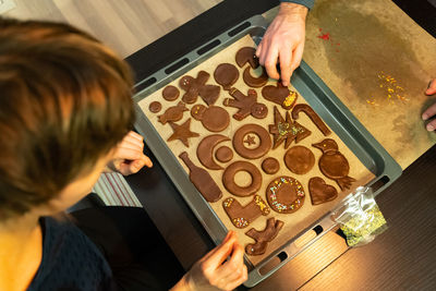 A woman and a man decorate a festive gingerbread cookie before christmas