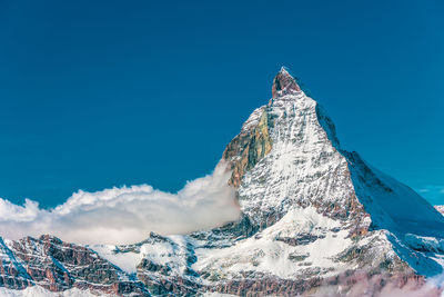 Panoramic view of snowcapped mountains against blue sky