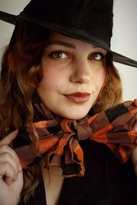 Portrait of young woman wearing witch costume against wall