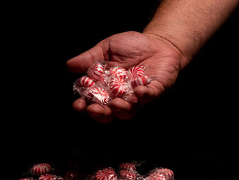 Close-up of person holding hands over black background