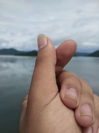 Close-up of human hand against rippled water