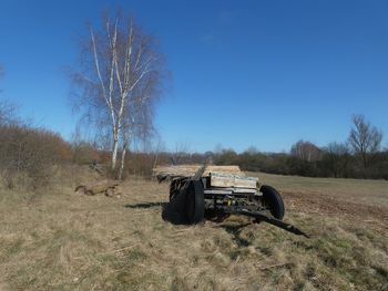 Abandoned truck on field against clear blue sky