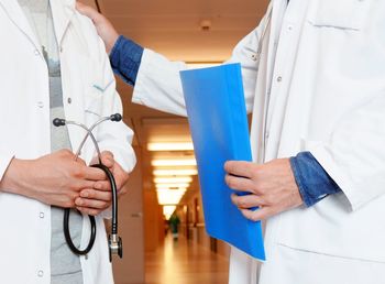 Male doctors discussing on document at corridor in hospital