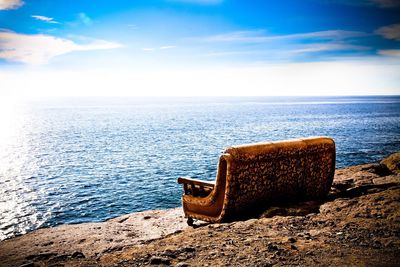Lounge chair by sea against sky