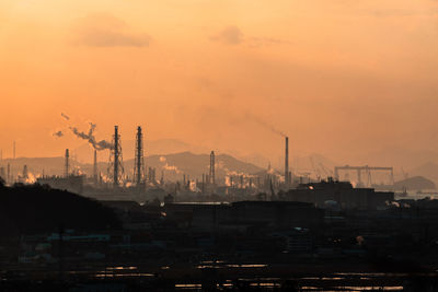 Smoke emitting from factory against sky during sunset