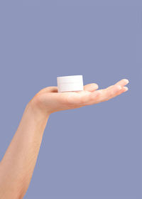 Cropped hand of woman holding pills against blue background