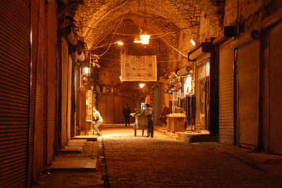 People walking on illuminated street amidst buildings at night