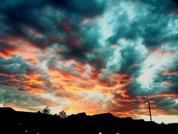 Low angle view of silhouette trees against dramatic sky