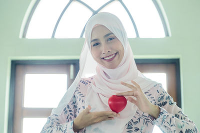 Portrait of a smiling young woman holding camera