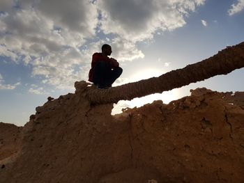 Low angle view of man sitting on rock