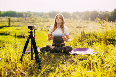 The girl practices yoga in nature and records a video lesson about yoga. yoga online