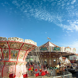 Low angle view of amusement park against blue sky