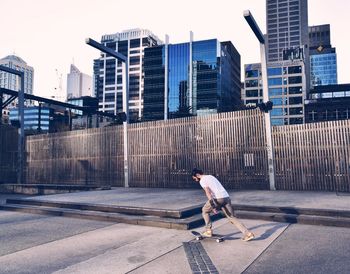 Side view of man on street against buildings in city