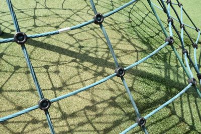 Playground where the sun makes shadow lines on the green floor below