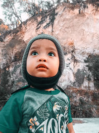 Close-up of cute boy in knit hat looking up outdoors