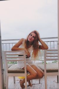 Portrait of young woman sitting on railing