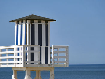 Built structure by sea against clear blue sky