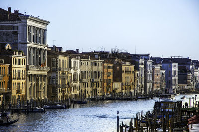 Canal in city against clear sky