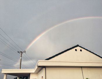 Low angle view of rainbow over roof against sky