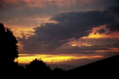 Low angle view of silhouette trees against dramatic sky