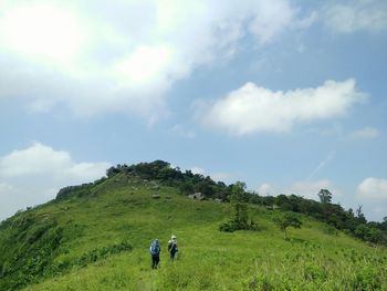 Rear view of people on landscape against sky