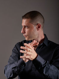 Side view of man looking away against gray background