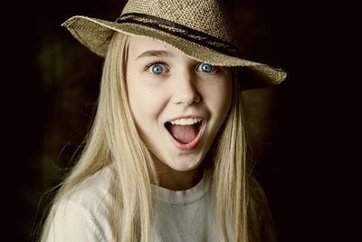 Portrait of shocked girl in hat against black background