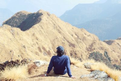 Rear view of man standing on mountain against sky