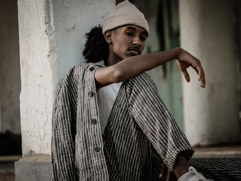 Side view of young man standing against wall