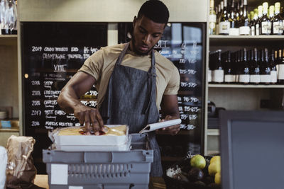 Male owner arranging order in box container at deli shop