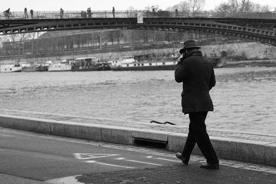 Rear view of man standing on bridge over river