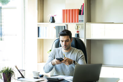 Businessman using mobile phone while sitting at office